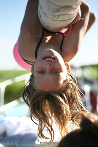 Close-up portrait of teenage girl hanging upside down at playground