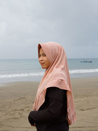 Woan standing on beach against sky
