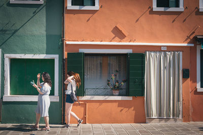 Woman standing on footpath against building