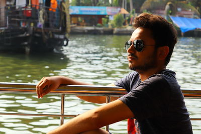 Young man posing in sunglasses at a harbour