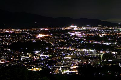 Illuminated cityscape against sky at night