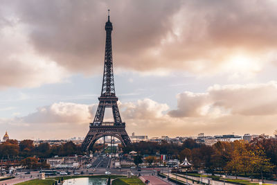 Communications tower in city against cloudy sky