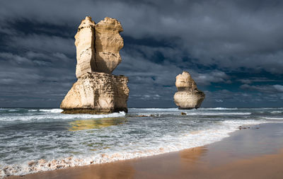 Rock formation on beach against sky