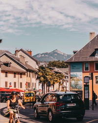 Cars on street by buildings in city against sky