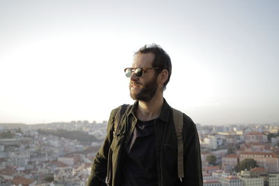 Man looking away while standing against clear sky