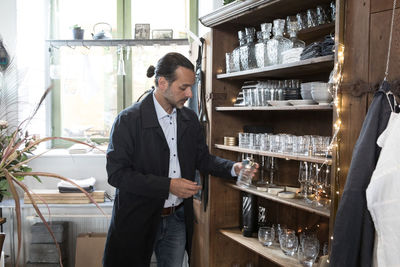Mature male customer choosing glass container from shelf at store