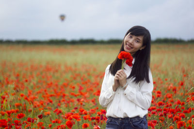 Woman standing on poppy field