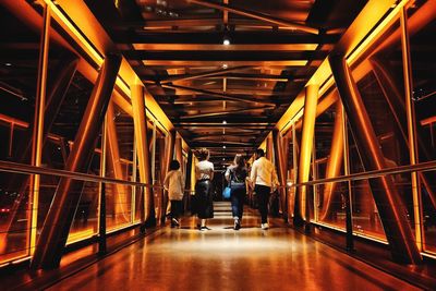 Rear view of people walking in illuminated building