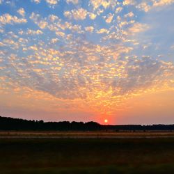 Scenic view of silhouette field against sky at sunset