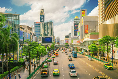 Traffic on city street by buildings against sky