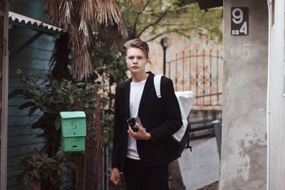 Portrait of young man standing against wall