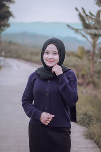 Portrait of smiling woman wearing hijab standing on road