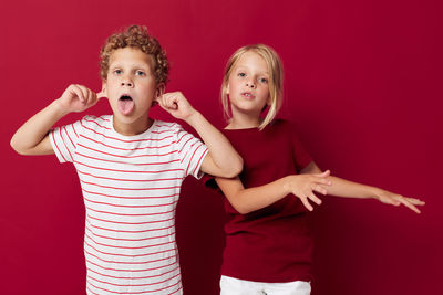 Portrait of smiling sibling against red background