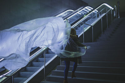 Rear view of woman holding plastic on steps