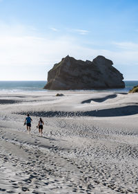 Couple running toward the water of wharariki beach, new zealand