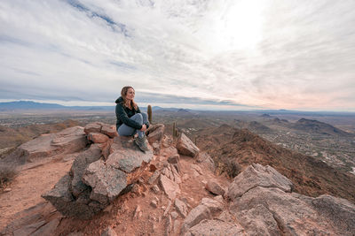 Full length of woman sitting on rock against sky