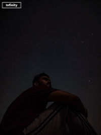 Low angle view of man looking away against sky at night