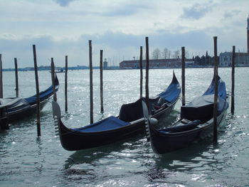 Boats moored on wooden post in sea