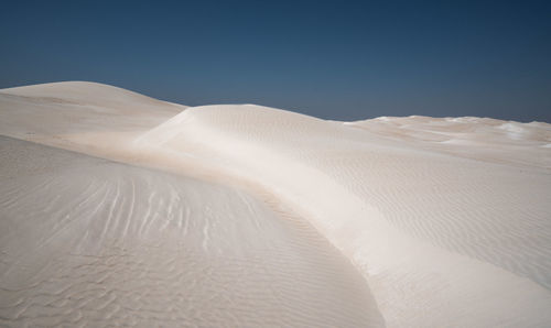 Sand dunes in desert against clear sky