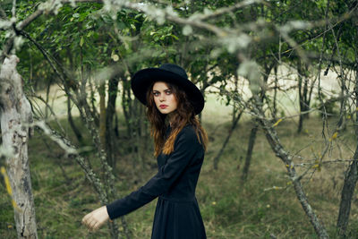 Portrait of beautiful young woman standing against trees