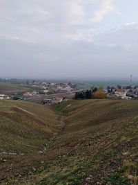 Scenic view of field against sky in city