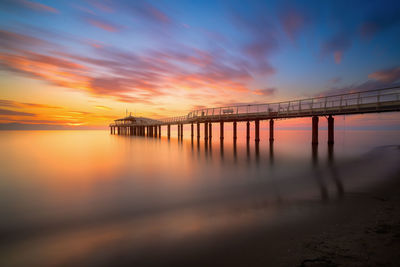 Bridge over sea against sky during sunset