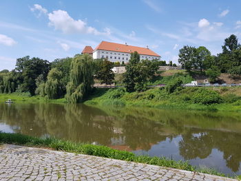 Reflection of trees and building in lake against sky