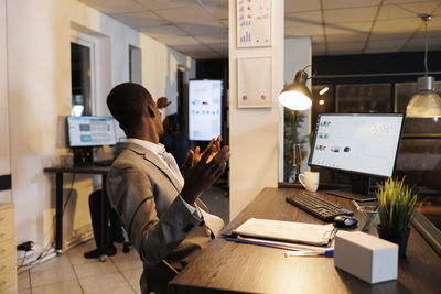 Rear view of woman using laptop at office