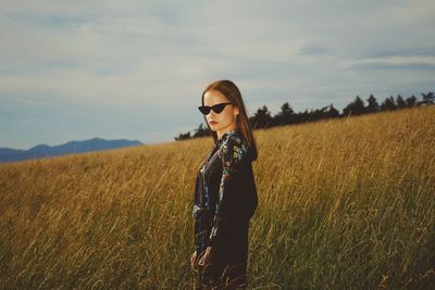 Portrait of young woman wearing sunglasses standing on field