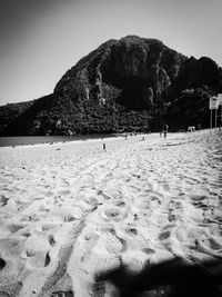 Footprints on sand at beach against clear sky