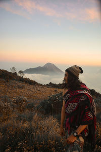 Man standing on mountain against sky during sunset