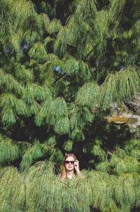 Portrait of young woman in sunglasses on tree