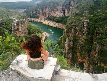 Rear view of woman sitting on rock