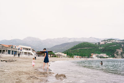 People on beach against clear sky