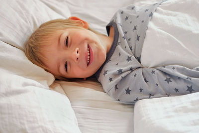 Portrait of 5 years boy in pajamas in the light bedroom. child making face. funny foolishness person