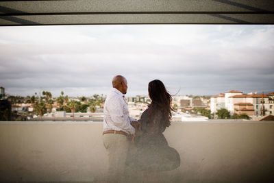 Rear view of woman looking at cityscape against sky