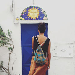 Rear view of woman standing against blue wall