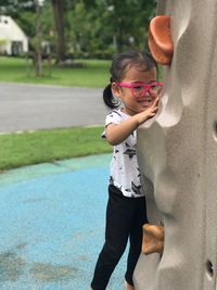 Cute girl standing by climbing wall in playground