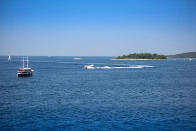 Sailboats sailing in sea against clear blue sky