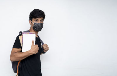 Portrait of young man standing against white background