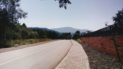 Road by trees against clear sky