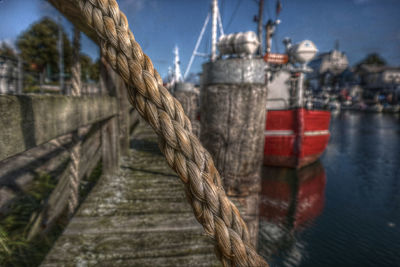 Close-up of wooden post at harbor against sky