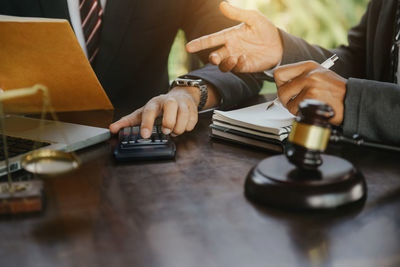 Midsection of lawyer holding gavel on table