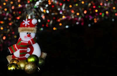 Close-up of snowman with christmas trees in background