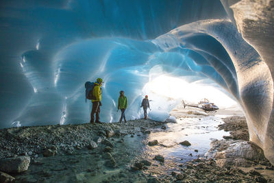 Adventure guide shows two female clients into a glacial cave.