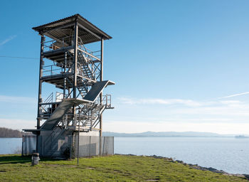 Traditional windmill by sea against sky