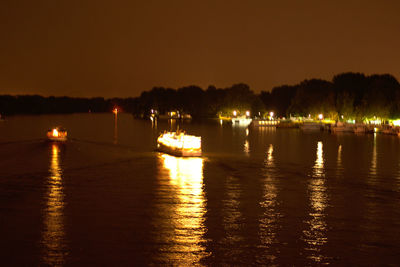 Boats moored in river at night