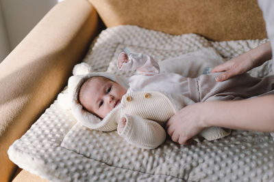 Mom dresses cute newborn little baby boy in a jumpsuit.