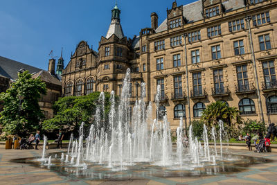 Fountain in city against sky