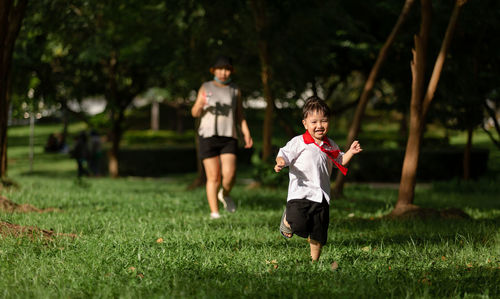 Full length of boy running on field with mother